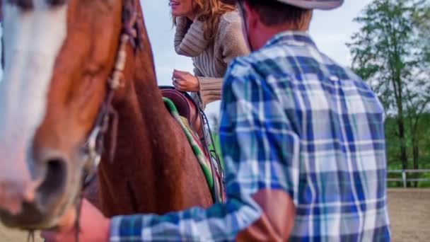 Muž pomáhá žena vyšplhat nahoru na koně — Stock video