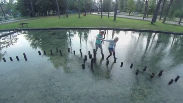 garçon et fille marchant sur les souches dans l'eau 