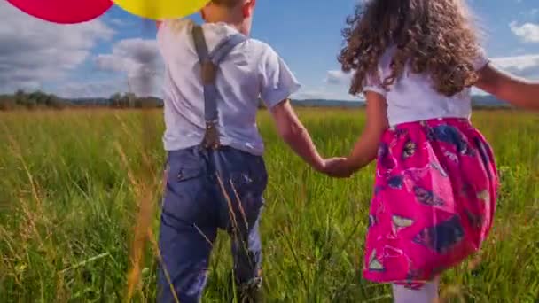 Мальчик и девочка с воздушными шарами, бегущими от камеры — стоковое видео