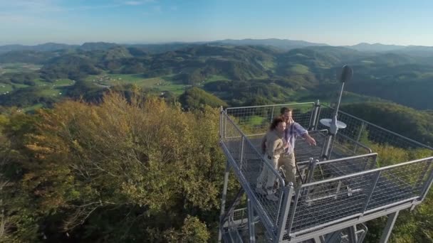 Paar op een uitkijktoren in het midden van een mooi landschap — Stockvideo