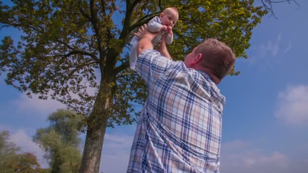 Человек под деревом бросает ребенка — стоковое видео