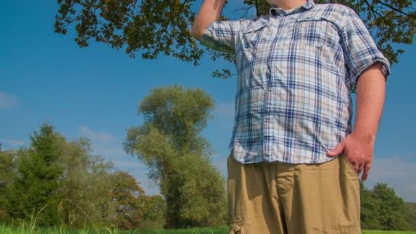 Inclinarse hacia el hombre mirando en la distancia en la naturaleza — Vídeo de stock