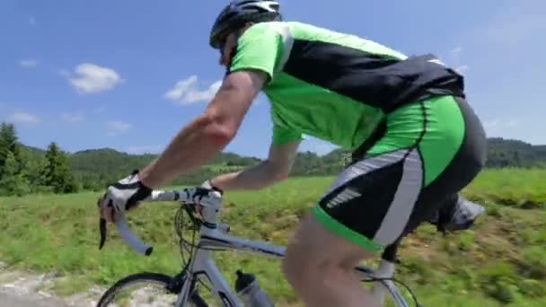 За велосипедистом в гору под низким углом — стоковое видео