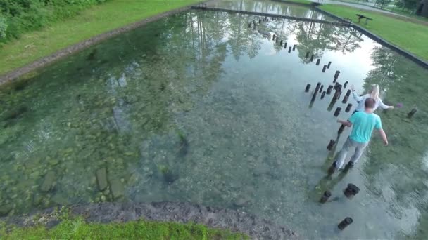 garçon et fille marcher sur souches dans l'eau 