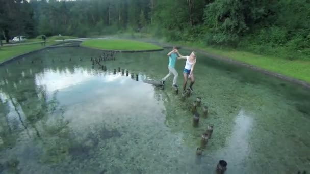 garçon et fille marchant sur les souches dans l'eau 