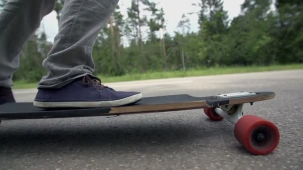 Člověk jede na skateboardu na silnici — Stock video