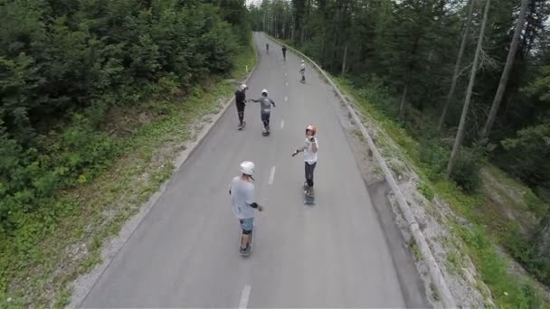 Grupo de patinadores de longboard que conduzem na estrada florestal — Vídeo de Stock