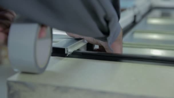 Hombre pone cinta adhesiva en marco de ventana — Vídeos de Stock