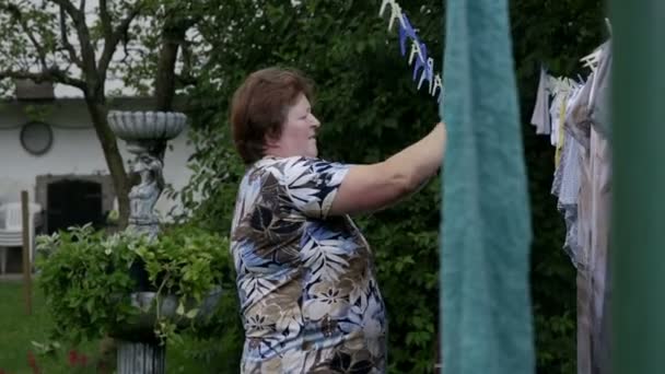 Frau hängt Wäsche an Wäscheleine — Stockvideo