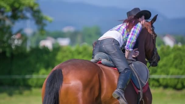 Una joven se sube a un caballo — Vídeos de Stock