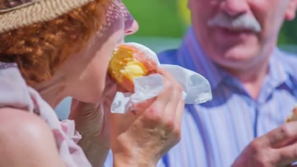 Een ouder echtpaar is het eten van donuts — Stockvideo