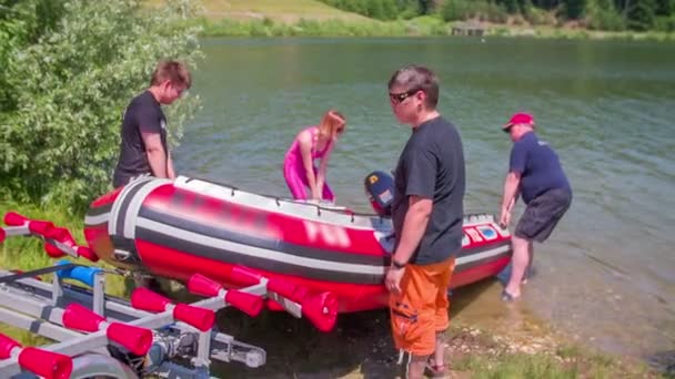Люди толкают резиновую лодку в озеро — стоковое видео