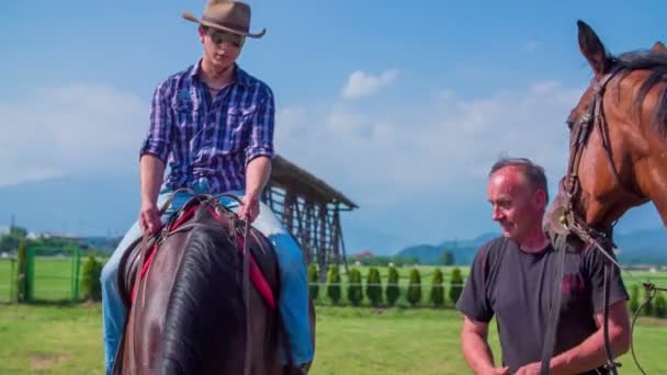 Un giovane ragazzo è seduto su un cavallo fermo — Video Stock