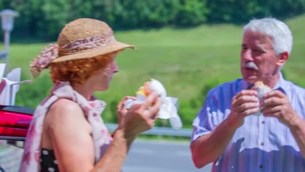 Una pareja mayor está disfrutando comiendo donas — Vídeos de Stock