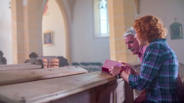 Couple sitting in pew and opening the Bible — Stok video