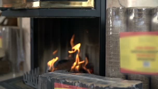 Burning fireplace surrounded with packages of briquettes — Stock Video
