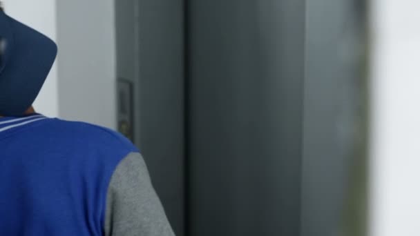 Jeune en attente de l'arrivée d'un ascenseur 