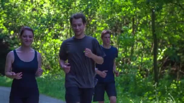 Una joven pareja corre por el bosque — Vídeos de Stock
