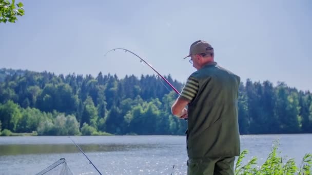 Pescador está pescando pacientemente en el lago — Vídeos de Stock