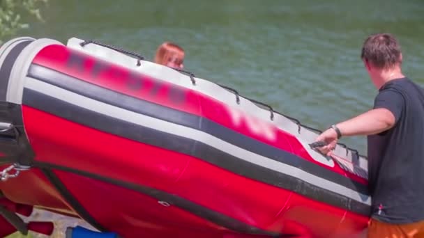 As pessoas estão tentando empurrar um barco de borracha para o lago — Vídeo de Stock