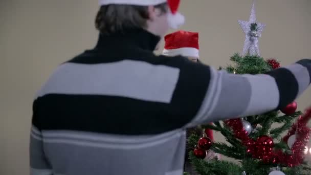 Пара прикрашає різдвяну ялинку — стокове відео