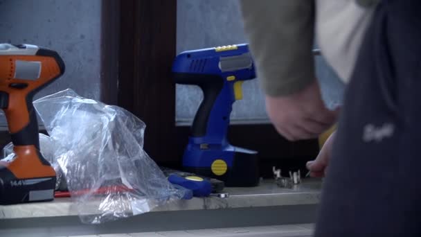 Man pikt enkele schroeven onder de tools — Stockvideo