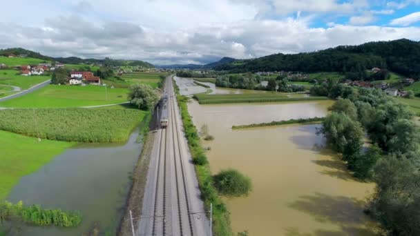 Flyga över tågspåren med tåg i översvämmad dal — Stockvideo