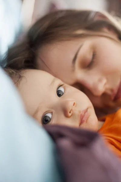 Despierta bebé niño con durmiendo mamá en la cama —  Fotos de Stock