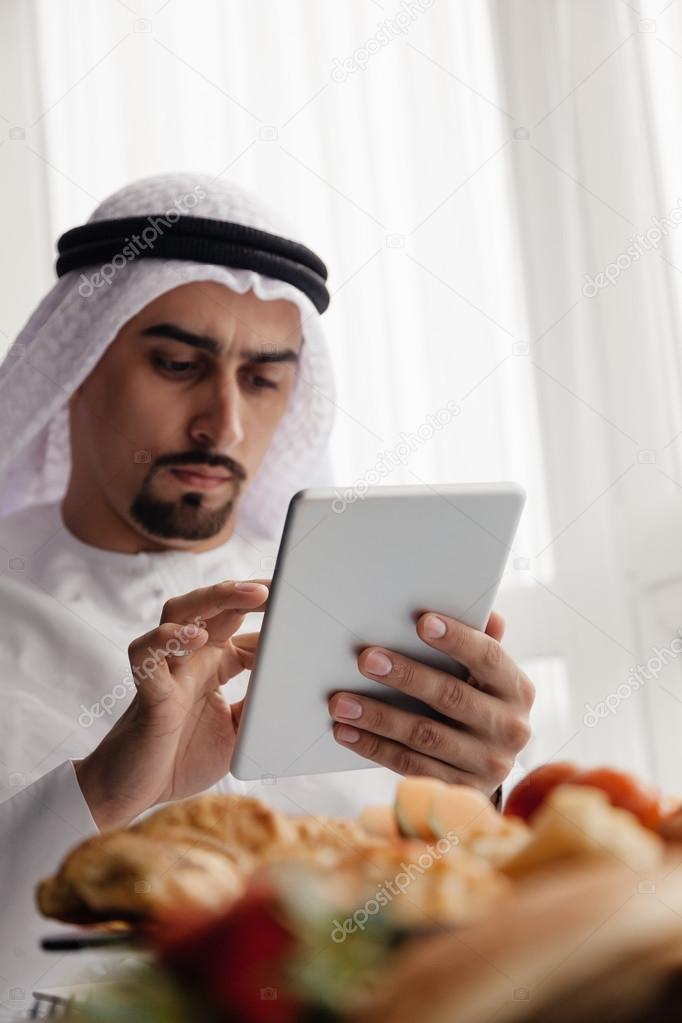 Arabian Male Using Tablet During Breakfast