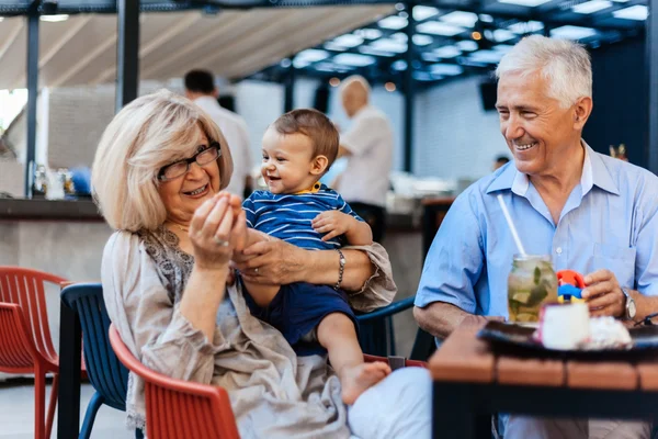Бабушка и дедушка с внуком в кафе — стоковое фото