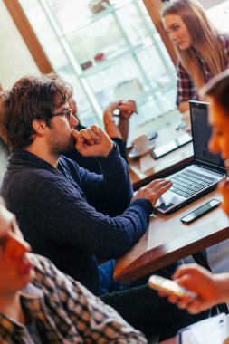 Kafede dizüstü bilgisayar kullanan genç adam.