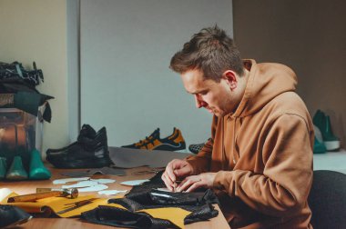 Bir ayakkabıcının spor ayakkabı yapma süreci. Ayakkabı tasarımcısı deriden bir desen çiziyor.