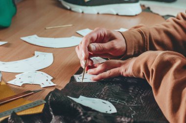 Atölyesinde siyah deriden desenler çizen kunduracıların ellerini kapatın.