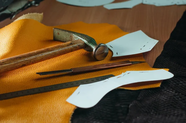Tools of shoemaker, pattern and leather on the table in workshop