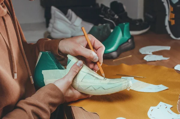 Close up of shoemaker drawing on the shoe. The process of making a sneaker by a shoemaker.