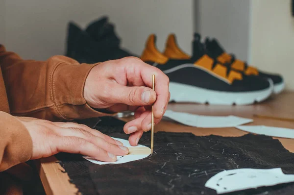 Shoemakers hands making patterns from leather in his workshop