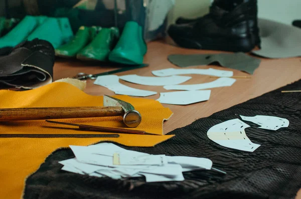 Tools of shoemaker, pattern and leather on the table in workshop