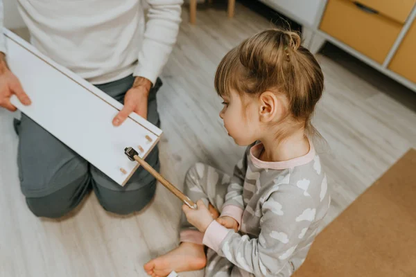 Tochter mit Hammer hilft ihrem Vater die Schublade des Kinderbettes zu reparieren — Stockfoto