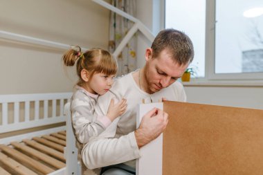4 yaşındaki küçük bir kız, babasının yatak odasındaki yatağı monte etmesine ya da tamir etmesine yardım eder..