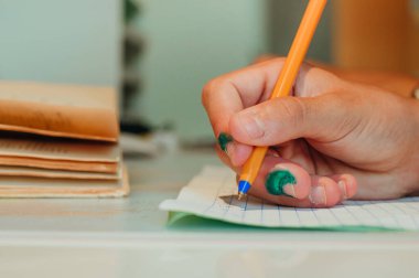 Ergen çocuğun el yazısıyla egzersiz kitabına ödevini yaparken yakın plan..