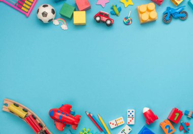 Mavi arka planda ahşap ve plastik çocuk oyuncakları çerçevesi ve mesaj için boş alan. Üst manzara, düz uzanma.