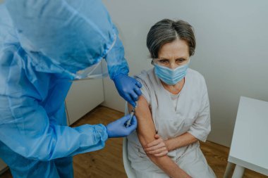 COVID-19 aşısı yapan koruyucu doktor ve eldivenler.