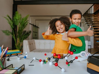 Kız ve erkek kardeş okul ekipmanlarıyla birlikte oturma odasında durarak eğleniyorlar. Okul konseptine dönelim..