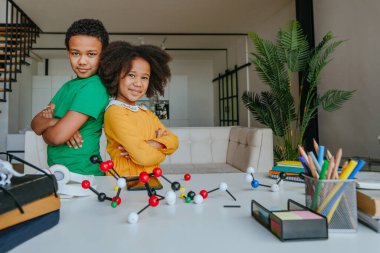 Kız ve erkek kardeş okul ekipmanlarıyla birlikte oturma odasında durarak eğleniyorlar. Okul konseptine dönelim..