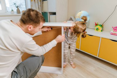 4 yaşındaki küçük bir kız, babasının yatak odasındaki yatağı monte etmesine ya da tamir etmesine yardım eder..