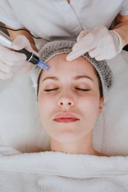 Güzellik salonunda yüz temizleme prosedürü uygulayan bir estetisyen.