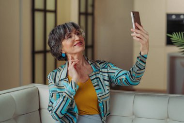 Video araması için akıllı telefon kullanan son sınıf öğrencisi şık bir kadın.