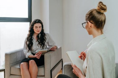 Genç bayan antrenör ya da antrenör stajyeriyle içeride görüşüyor.