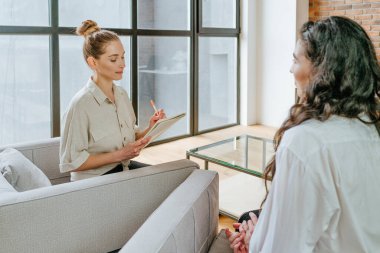 Bayan antrenör, stajyeriyle röportaj yapıyor ve not defterine notlar yazıyor. Seçici odak.