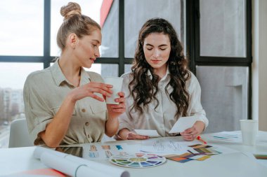 Moda tasarımcıları kıyafet modellerinin resimlerini seçiyor ve ofiste yeni koleksiyonu tartışıyorlar. Seçici odak.